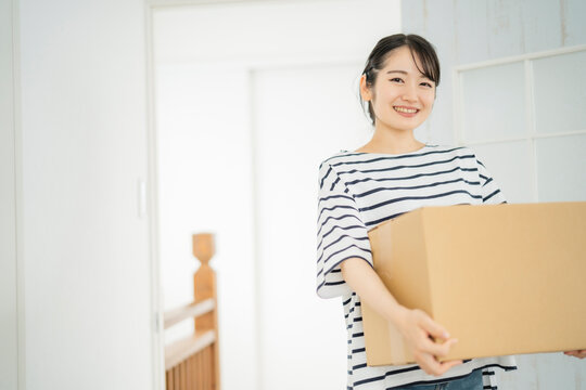 段ボールを運ぶ女性（笑顔）
