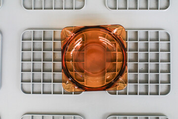 Clean round glass ashtray on grey plastic box. The concept of the harm of smoking. Close up,...