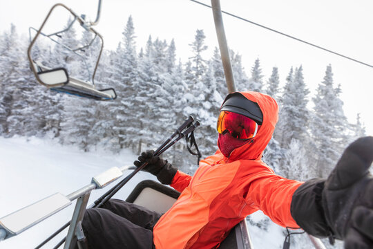 Ski vacation - skier in ski lift taking selfie photo or video using mobile phone. Ski winter vacation concept. Skiing on snow slopes in mountains, Woman having fun on snowy day. Winter sport activity