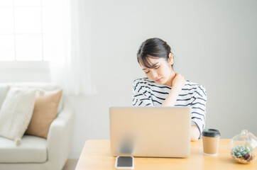 家でパソコンを使う女性（体調不良の女性）
