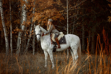 Beautiful young woman in English hunter wear style with Knabstrupper horse and Irish setter at autumn park - 469624442
