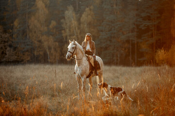 Beautiful young woman in English hunter wear style with Knabstrupper horse and Irish setter at autumn park - 469624444