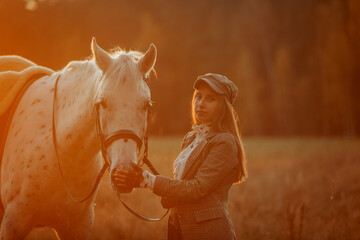 Beautiful young woman in English hunter wear style with Knabstrupper horse and Irish setter at autumn park