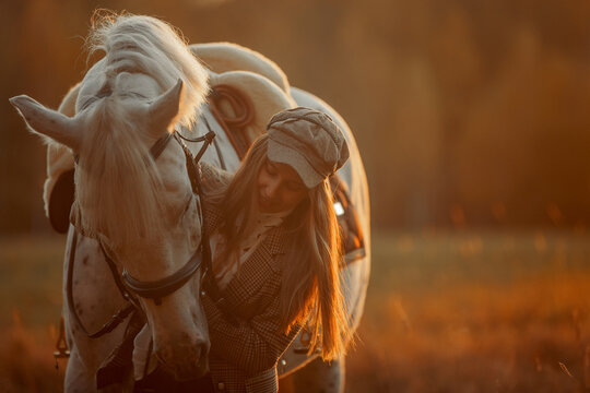 Beautiful young woman in English hunter wear style with Knabstrupper horse and Irish setter at autumn park