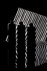 Still life with three bottles on a striped background with reflection