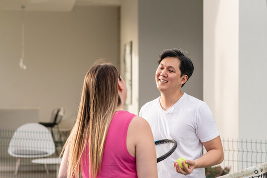 Asian Man Trying To Woo Caucasian Woman After Playing Tenis Outdoors