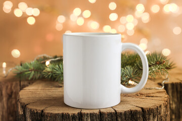 Obraz na płótnie Canvas White cup on a wooden background with fir branches close-up front view. Mockup for design, template for logo with copy space.