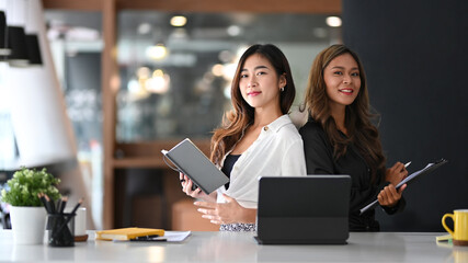 Cheerful business colleagues sitting in modern office and smiling to camera.
