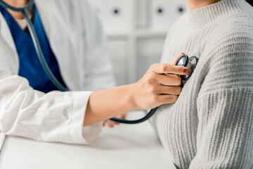 Close up of Female Doctor using stethoscope putting beat heart diagnose with patient in examination...