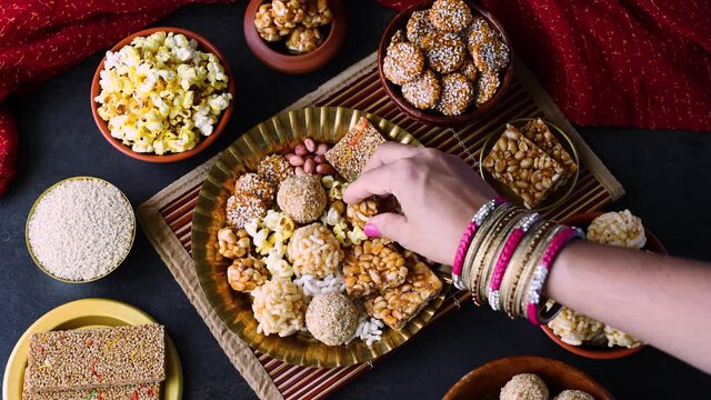 Til chikki Murmura ladoo woman hand serving peanut chikki laddu Revdi popcorn Indian festival snack sweet Lohri Makar Sankranti Pongal Diwali 4K video footage winter food Tamil Nadu Punjab India