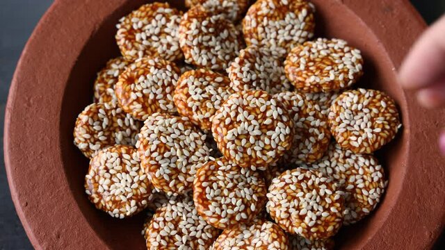 Revdi revri til gud revdi rewari sesame cookie woman hand serving winter food Indian festival food snack sweet Lohri Makar Sankranti Pongal Diwali 4K video footage harvest Tamil Nadu  Punjab India.