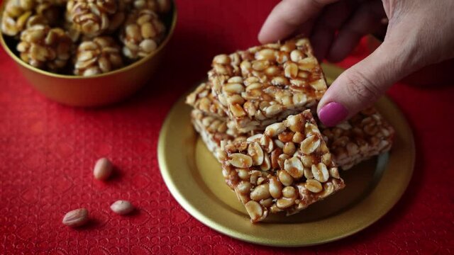 Peanut chikki peanut candy groundnut sweet Kadalai mittai woman hand serving winter food Indian festival food snack Lohri Makar Sankranti Pongal Diwali 4K video footage Tamil Nadu Punjab North India