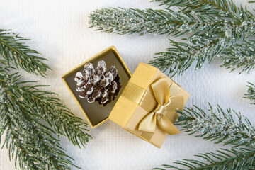 Fototapeta na wymiar New year and Christmas concept of holiday decorations. Small decorative Christmas pine cone in golden gift box