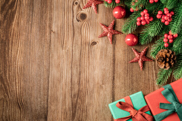 Top view of green branches, pine cones, Christmas gift box, stars, red balls, red berries on dark wooden background, Banner, copy space, Christmas or New Year background concept.