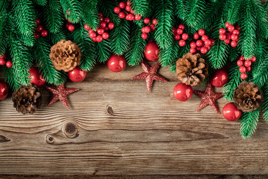 Top view of green branches, pine cones, Christmas stars, red balls, red berries on dark wooden background, Banner, copy space, Christmas or New Year background concept.