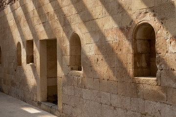 Fototapeta na wymiar Wall of an old palace with window openings and beautiful shadows