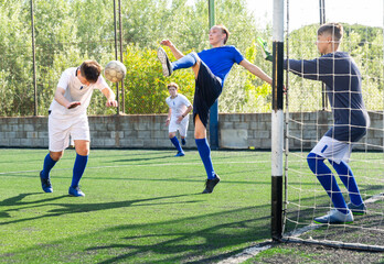 Young football players fighting for ball in goalmouth zone