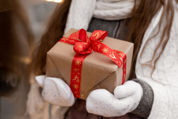 A sweet young girl with a gift looks out the shop window. New Year. Christmas. Atmosphere.