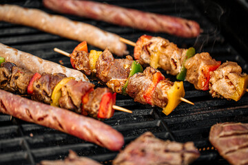Closeup on grilling sausages and chicken skewers on a barbecue