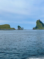 Fototapeta na wymiar View of the impressive Rocky Drangarnir sea stack and the fishing farms in the Faroe Islands seen from the ferry to Mykines 