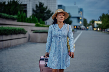 Fototapeta premium Asian woman walking with her luggage in a foreign city