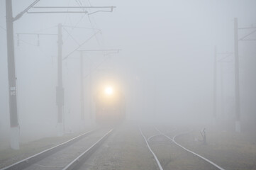 transportation train with yellow warm head light on railroad railway in dark mist fog haze
