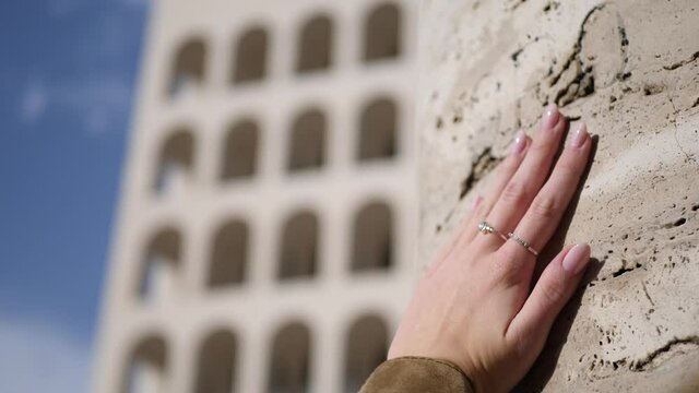 Mano che accarezza colonna antica di marmo travertino. Arte e monumenti. sullo sfondo il colosseo Quadrato a Roma.
Immagine evocativa di arte e bellezza.