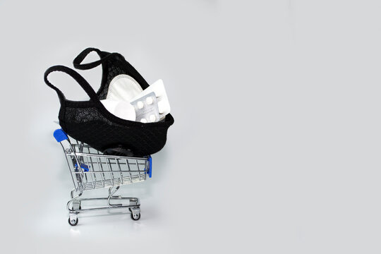 Second And Third Waves Of Coronavirus. Medical Mask, Disposable Gloves, Antiseptic And Electronic Thermometer On A Dark Background In A Shopping Cart.