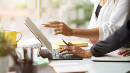 Two businesswomen speaking in a meeting and working on a digital tablet