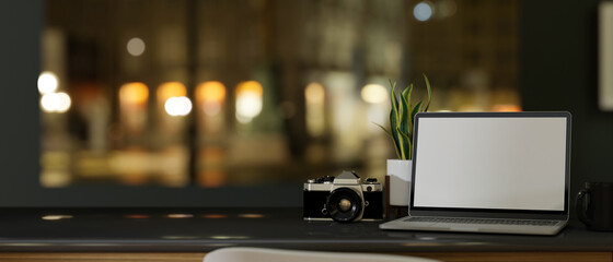 Modern dark hipster working desk with laptop over blurred night light background.
