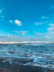 Waves on the sea on the shore against the blue sky during the day. Foam waves.