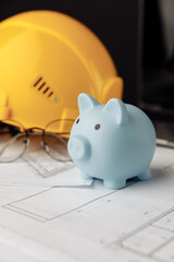 House building costs concept. Safety helmet and piggy bank close-up. Vertical image