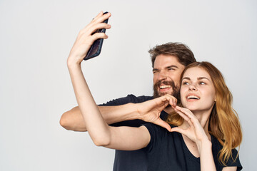 cheerful young couple in black t-shirts phone fun together friendship light background