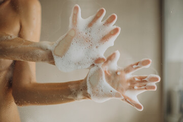 Female hands with foam on shower glass