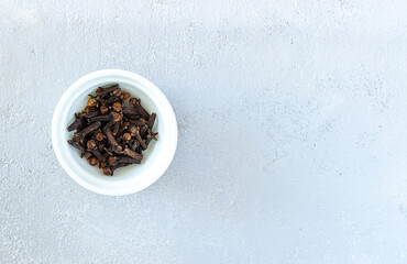 Dry cloves spices in white plate isolated on gray background. High quality photo