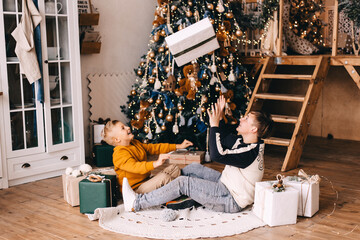 two boys are plaing with the gift under christmas tree - obrazy, fototapety, plakaty