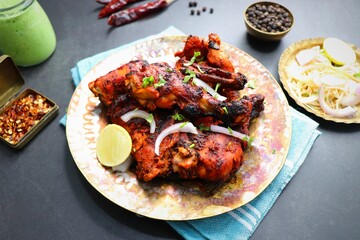 Tandoori chicken is a popular roast chicken recipe from India.   Tandoor is a traditional wood oven. Chicken Tandoori Platter is served in a brass plate with salad and spices. Copy Space. 