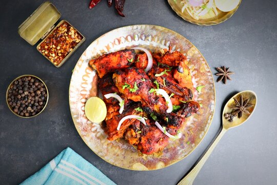Tandoori chicken is a popular roast chicken recipe from India.   Tandoor is a traditional wood oven. Chicken Tandoori Platter is served in a brass plate with salad and spices. Copy Space. 