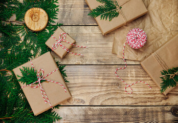 Boxes packed in kraft paper, branches on a wooden background. Environmentally friendly material.Christmas and New Year.