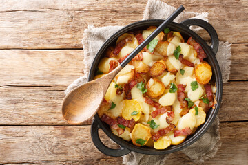 Fresh Aubrac truffade potatoes with cheese and bacon close up in the pan on the table. Horizontal...