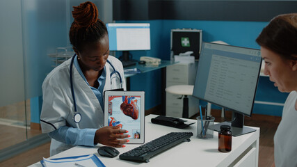 African american doctor showing cardiovasular image on tablet to patient for cardiology diagnosis....