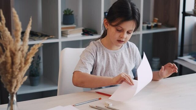 Artistic hobby. Creative girl. Painting school. Pretty female kid start drawing with pencil on white paper in light studio interior.
