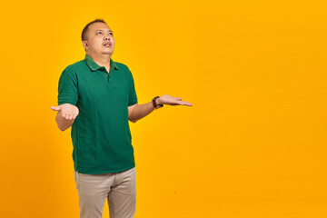 Portrait of asian man surprised with confused and displeased expression on yellow background