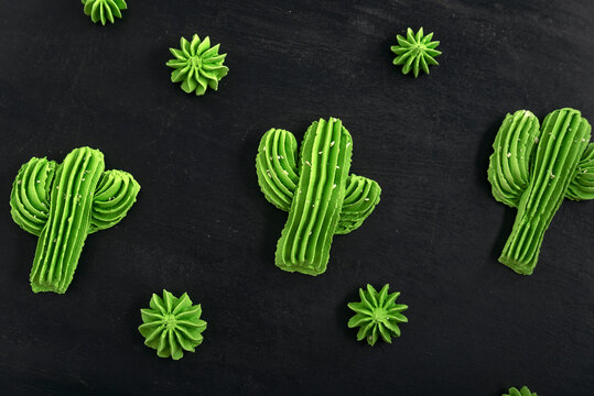 Green air cookies in the form of cactus. French dessert meringe on black table.