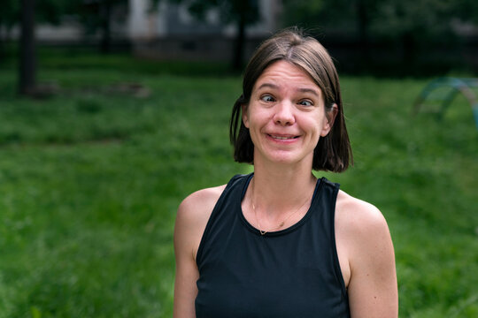 Young Girl Writhes Her Faces. People With Developmental Disabilities And Disabilities. Outdoors