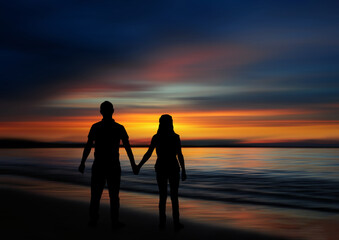 Sunset silhouette of a couple holding hands on the beach