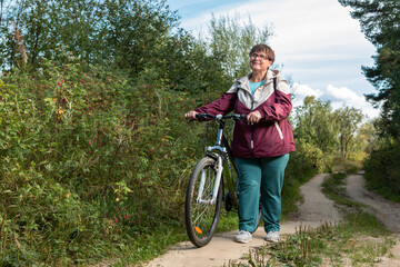 Cheerful grandmother rides a bicycle in nature.