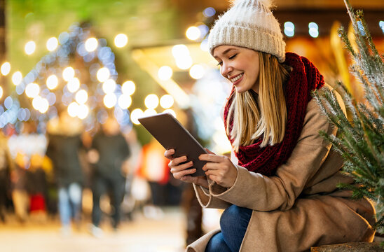 Shopping christmas travel people concept. Happy woman with shopping bag using digital device outdoor