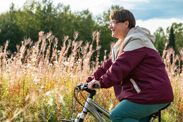 Cheerful grandmother rides a bicycle in nature.