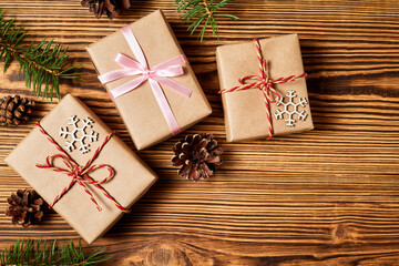 Christmas gift boxes on wooden background with pine cones and fir branches with copy space